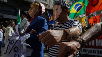 Manifestantes marchan con imgenes satricas del presidente estadounidense, Donald Trump, y del expresidente brasileo, Jair Bolsonaro, esposados, tras el anuncio de Trump de aranceles de 50 % a los productos brasileos por el juicio del exmandatario.