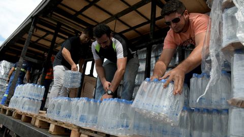 Voluntarios reparten botellas de agua para las personas afectadas despu�s de que la presa de desechos t�xicos de mineral de hierro fallase