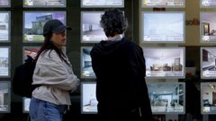 Unos viandantes consultan las ofertas en el escaparata de una inmobilaria