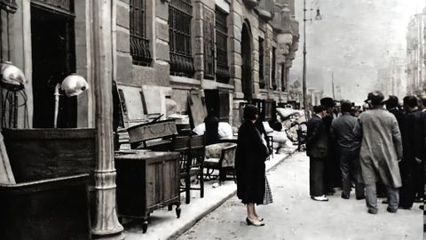 Oviedo, Octubre de 1934.  La revolucin ha sido sofocada en el centro de la ciudad y, tras muchos das encerrados, los vecinos salen a contemplar la devastacin causada por los combates. En la imagen la calle Fruela, con los muebles a la intemperie para salvarlos de los incendios.