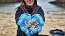 Una voluntaria limpiando de plets la playa coruesa de O Portio