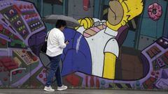 Una mujer se protege de la lluvia en Lugones