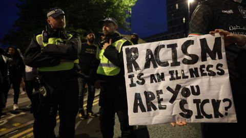 La polica observa a un manifestante antirracista que sostiene una pancarta en Walthamstow, al este de Londres, Gran Bretaa.