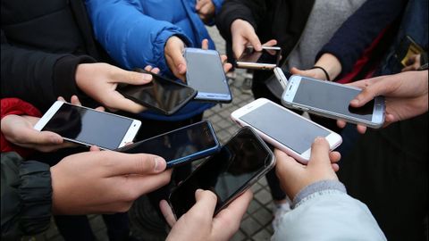 Un grupo de adolescentes mostrando sus teléfonos móviles