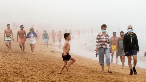 Ba�istas en la playa de San Lorenzo, en Gij�n, entre la niebla
