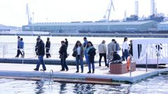 Ciudadanos en la nueva plataforma para baistas instalada en O Parrote; al fondo, el muelle de San Diego