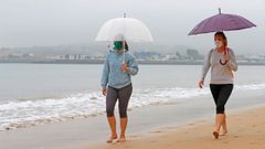 Unas personas pasean por la playa de Ssan Lorenzo de Gijon, durante la franja horaria permitida, hoy quincuag�simo sexto d�a del estado de alarma