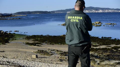 Un agente custodiando en mayo en Cambados un fardo que apareció en la playa de Tragove y que contenía harina en vez de cocaína. La investigación no descarta que pudiera pertenecer a los detenidos este miércoles.