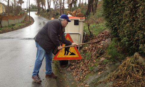 Uno de los afectados por las inundaciones en As Naveiras, retira las hojas de las cunetas. 