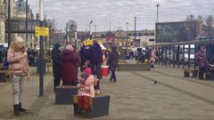 Una ni�a sentada junto a su madre cerca de la entrada de la estaci�n de trenes de Le�polis