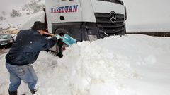 Un camionero trata de desploquear su camin de la nieve, en el pueblo de Pajares