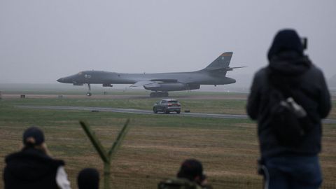 Curiosos observan desde el exterior el bombardero estadounidense que aterriz� ayer en la base de Fairford de Reino Unido. 