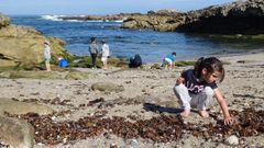 Una ni�a recogiendo plasticos en la playa