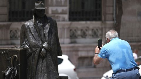 Un turista hace fotos a la escultura urbana conocida como El regreso de Williams B. Arrensberg en Oviedo