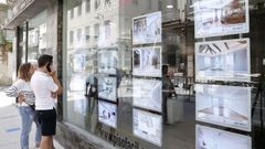Dos personas analizan las diferentes ofertas de casas y pisos que se ofrecen en una agencia situada en la ciudad de Lugo.