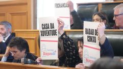 Concejales del PP muestran carteles con sus propuestas durante el pleno del Concello de Santiago sobre el estado del municipio
