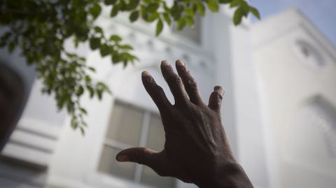 Un hombre alza su mano para predicar durante un improvisado servicio religioso en el exterior de la iglesia.
