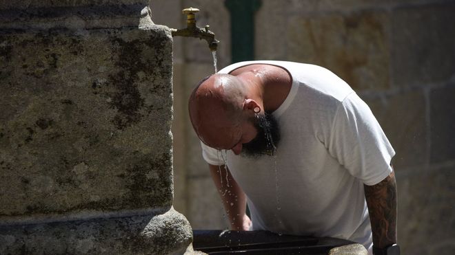 Un hombre se refresca en una fuente, en Combarro. 