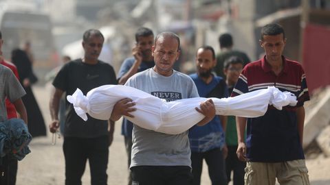 Un hombre porta el cadáver de un familiar muerto en Gaza.