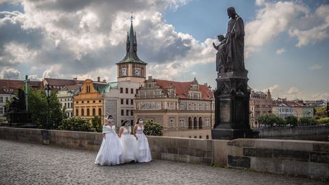 Tres modelos posan vestidas de novia en el puente de Carlos, en Praga, ataviadas con mascarillas