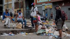 Un grupo de personas escarban entre la basura en una calle de Caracas