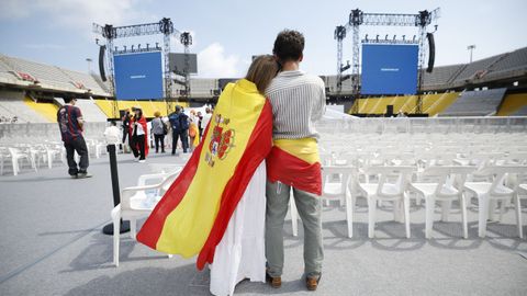 Dos personas esperan a que empiece la vigilia en el Estadio Ol�mpico.