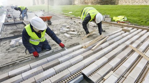 Los operarios colocando la parte mixta del paseo, que lleva baldosas y separadores biodegradables