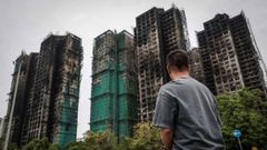 Un hombre observa las torres residenciales afectadas por el incendio