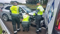 Tres agentes de Trfico de la Guardia Civil inspeccionan dos de los vehculos implicados.