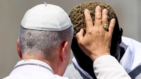El papa bendice a un migrante.
