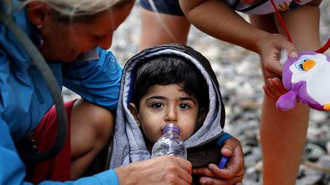 Una voluntaria ofrece agua a un nio sirio exhausto recin desembarcado en Lesbos.