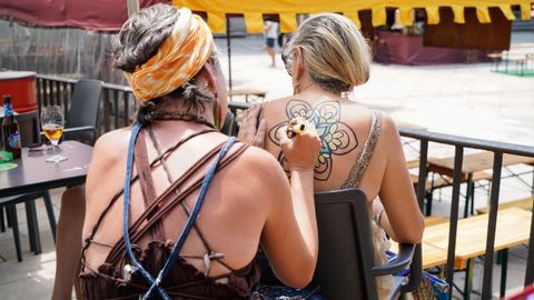 Una artista dibuja en la espalda de una clienta