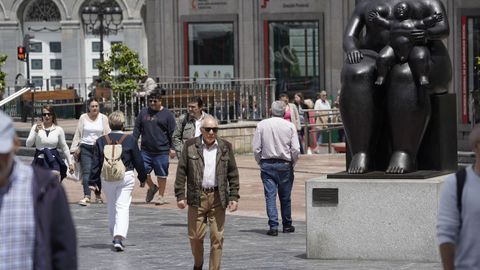 Paseantes por la plaza de la Escandalera con el Teatro Campoamor al fondo