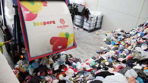Un cami�n de reciclaje de Koopera (C�ritas) deposita en su nave de Asturias la ropa recogida para clasificar, reutilizar o reciclar