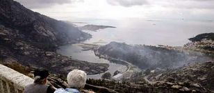 <span lang= es-es >Paisaje desolador</span>. Dos vecinas observan el desastre causado por el fuego en O �zaro.