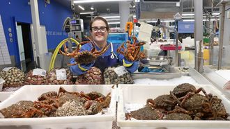 Manuela Pardavila, de Mariscos Bomar, muestra la centolla en el puesto de la plaza de abastos de Ribeira