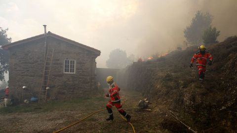 Los bomberos tratan de proteger una casa del fuego en el barrio de O Outeiro