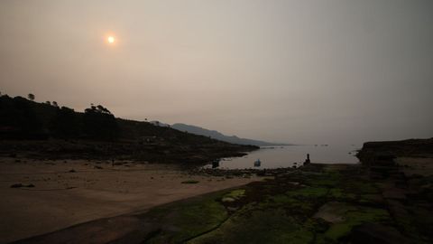 Sol a través del humo en Cee, desde la playa de Caneliñas