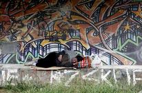 Un hombre descansa ante el muro exterior de las pistas de atletismo, en el paseo del Lagares.