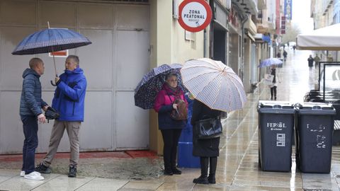Un grupo de personas hablando bajo sus paraguas el pasado viernes en la calle Real.