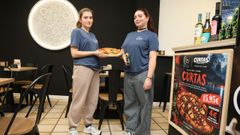 Empleadas del establecimiento con una Pizza Curtas reci&eacute;n hecha y el bote de salsa especial empleado para redondear su sabor.