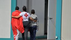 Una voluntaria de Cruz Roja acompaa a dos menores llegados este mes de julio a Canarias.