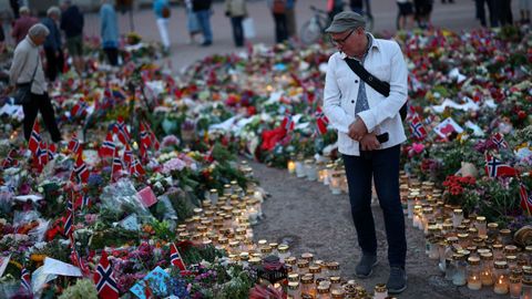 Un hombre camina entre las flores colocadas ante el palacio real de Oslo