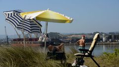 Varias personas toman el sol en la zona del Zeluan frente al puerto de Avils