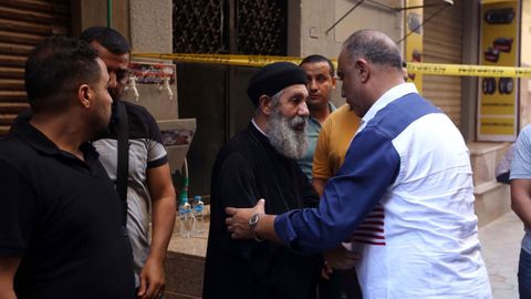 Vecinos confortan a un sacerdote copto tras el incendio de la iglesia de Abu Sifine en Egipto.