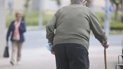 Un hombre mayor camina por una calle de Ferrol ayudado por un bastón