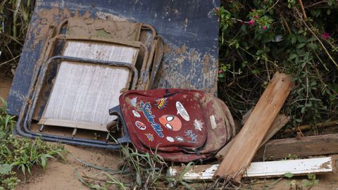 Enseres domésticos, entre ellos una silla y una mochila infantil, tirados en una calle de Valencia