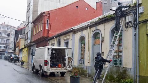 Dos operarios retiran el canal�n y las tejas del n�mero 4 de la calle Os Dur�ns para evitar accidentes despu�s de haber tapiado los accesos a la vivienda