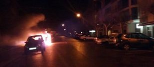 Imagen de los contenedores ardiendo, con veh�culos aparcados cerca. 