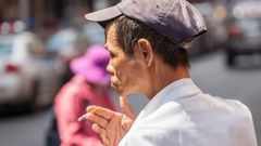 Un hombre chino pasea por la calle mientras fuma